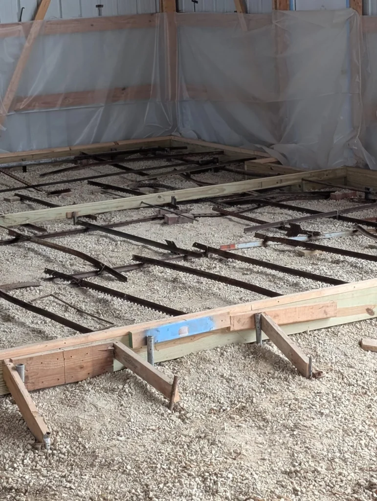 Garage floor concrete requirements in Calgary showing compacted gravel base and rebar reinforcement before pouring
