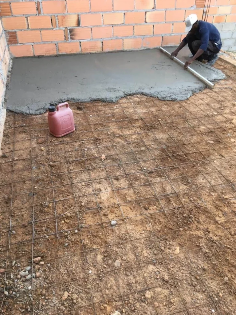 Basement concrete floor sub-base preparation with compacted soil and reinforcement
